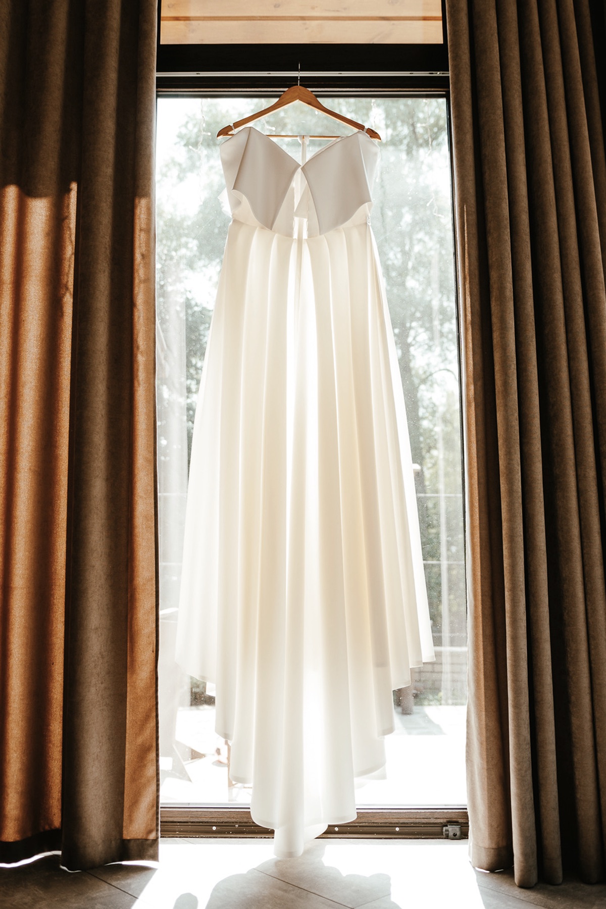 Brautkleid auf einem Bügel vor der Fensterfront im Get-Ready-Room