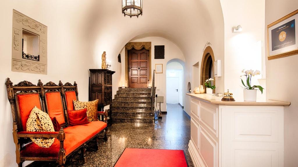 Empfangshalle des Schlosses mit Rezeptionstresen, historischer Bank und Treppe