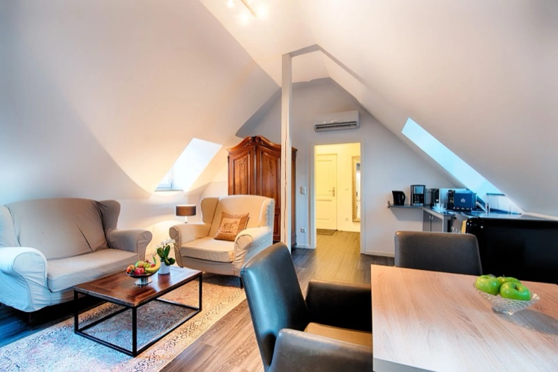 Wohnbereich des Appartements mit Sesseln und Kitchenette unter der Dachschräge