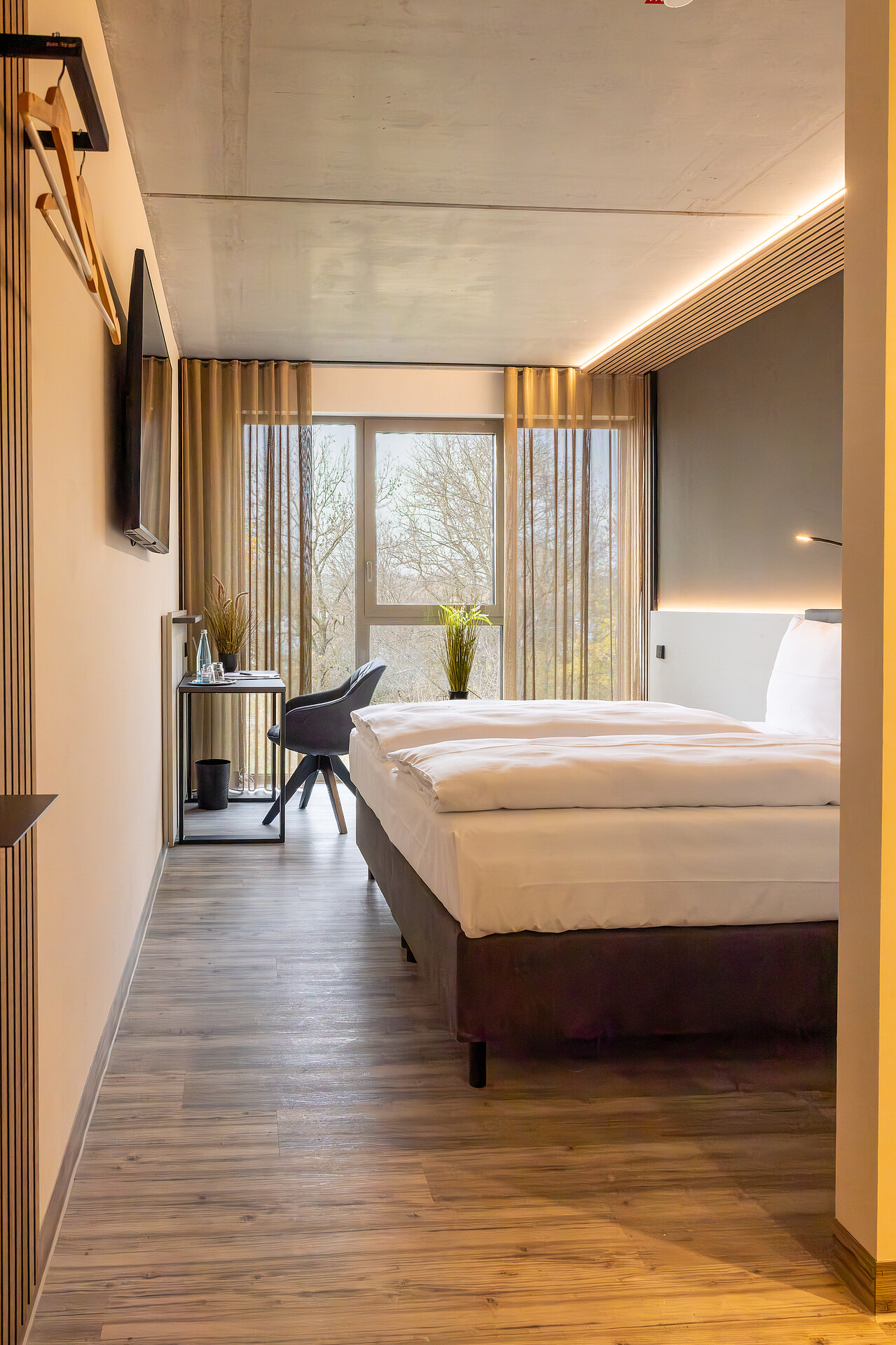 Neubauzimmer in ganzer Raumtiefe mit Bett, Schreibtisch und raumhohem Fenster
