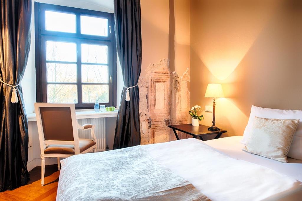 Kompaktes Altbauzimmer mit Einzelbett, Fenster ins Grüne und historischem Wandrelief
