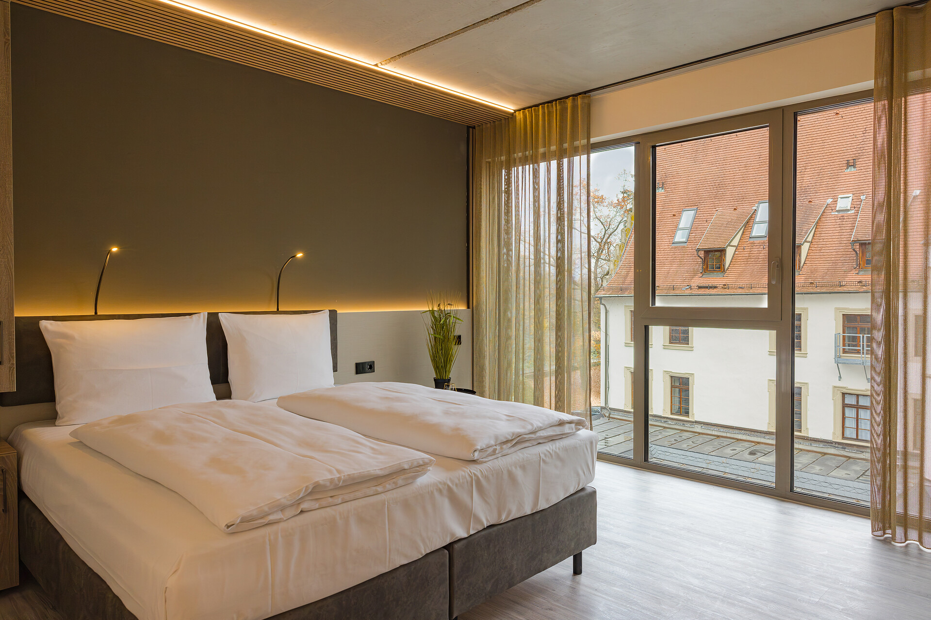 Premium Doppelzimmer im Neubau mit Boxspringbett vor großer Fensterfront