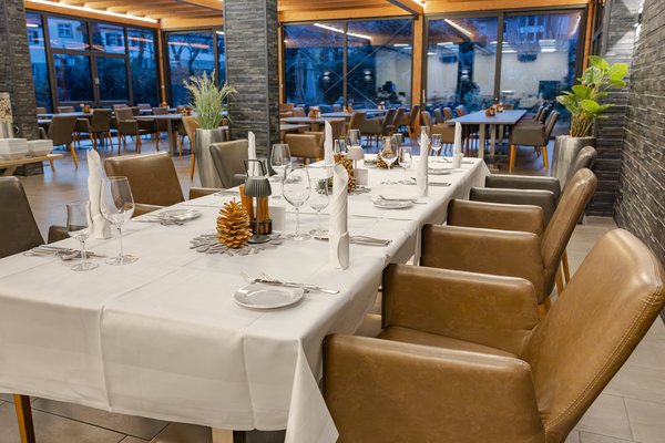 Lange, weiß eingedeckte Tafel mit Kerzen im Wintergarten zur blauen Stunde