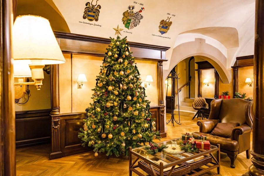 Festlich geschmückter Weihnachtsbaum in der Lobby, davor Ledersessel und Geschenke